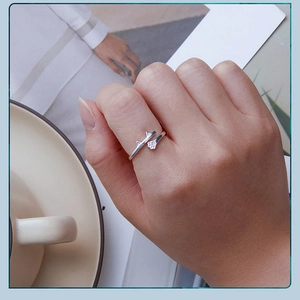 Close-up of S925 silver cat-ear ring with pink paw print on hand with a coffee cup