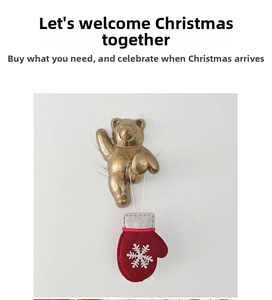 Detailed view of a brass bear wall hook holding a festive red and white snowflake mitten