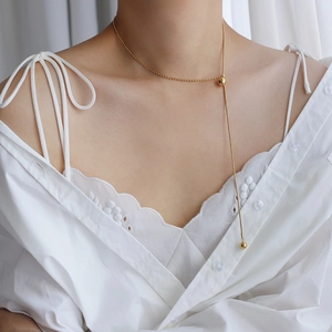 Detailed view of adjustable 18K gold snake chain necklace with beaded tassels on a model