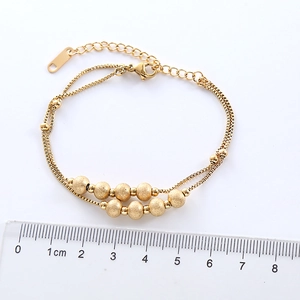 Double-layered gold stainless steel bracelet with frosted round beads on white background