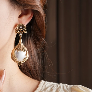Gros plan d'une boucle d'oreille fleur vintage dorée avec diamants et perle nacrée