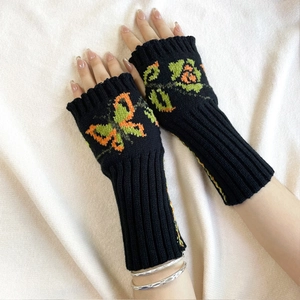 Close-up of knit fingerless gloves with colorful butterfly and floral crochet patterns