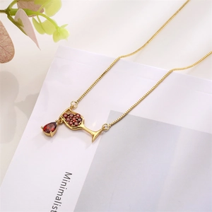 Detailed view of a gold wine glass pendant necklace with red zircon stones on white background