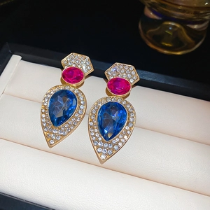 Détail de boucles d'oreilles vintage dorées avec gemmes bleues et touches roses