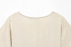 Close-up of beige round neck midi dress featuring intricate lace texture and satin fabric