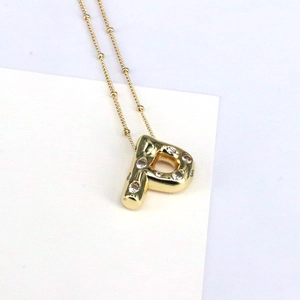 Close-up of 18K gold letter P pendant necklace with cubic zirconia on a bead chain