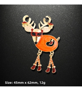 Macro detail of Christmas reindeer brooch with orange enamel and red glitter accents