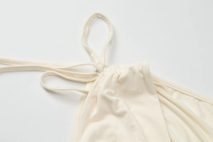 Dettaglio del crop top color crema che mostra spalline sottili e tessuto con arricciature