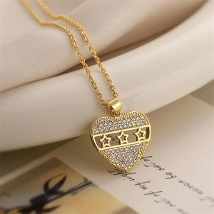 Detail of gold heart pendant with inlaid zircons and star cutouts on silk background