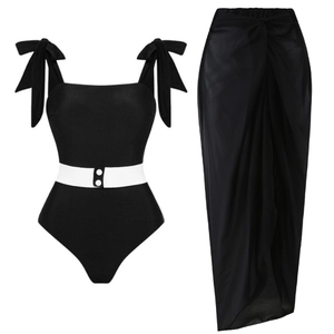 Dettaglio del costume intero nero con fiocchi sulle spalle e pareo da spiaggia velato