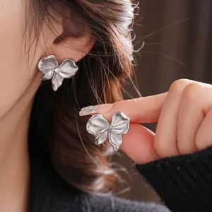 Silver bow stud earrings with pleated metal texture and sparkling center zircon crystal