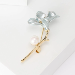 Close-up of gold flower brooch with light blue enamel petals and white pearl detail