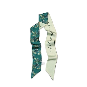 Detail of floral silk scarf showing green leaf print and cursive text patterns