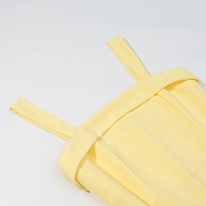 Détail rapproché des coutures fines et de la texture fluide du tissu jaune de la robe