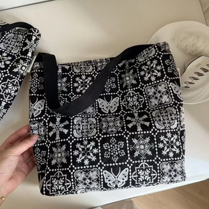 Close-up of black and white butterfly embroidery patterns on canvas tote bag fabric