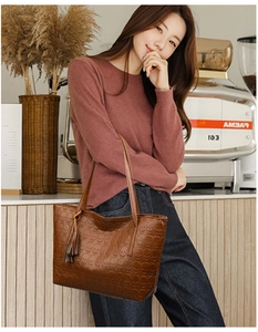 Close-up of brown leather tote bag with skull embossed texture and stylish fringe detail