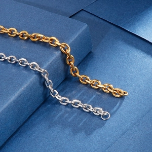 Macro shot of 18k gold and silver stainless steel link chains on a blue background