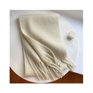 Detailed view of thick cream mohair scarf with fringes on a minimalist table