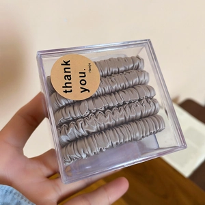 Five-piece silver satin scrunchie set in a transparent gift box with a thank you sticker