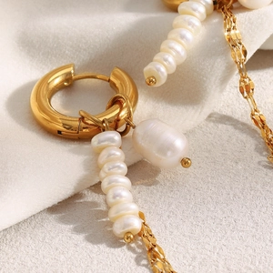Close-up of 18K gold plated hoop earrings with pearl chain tassels on soft white fabric