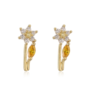 Detail view of floral gold earrings with white petals and yellow zircon gemstones