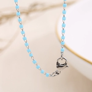 Close-up of light blue enamel beads on silver chain necklace with lobster clasp detail