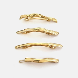 Gold metal hair clips with hammered texture and wavy design on white background