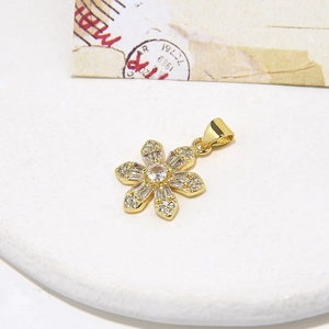 Minimalist gold flower pendant necklace with white zircon petals on a textured surface