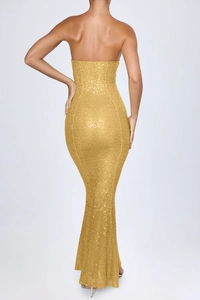 Detail of sequined back and backless mermaid cut of a golden evening gown dress