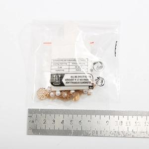Detailed view of the gold pearl necklace with rhinestone tassel against a ruler for sizing