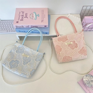 Détail de la broderie florale de rose sur sacs en toile à carreaux avec chaîne en perles
