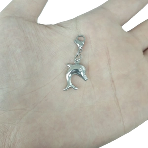 Silver hollow dolphin pendant with lobster clasp shown on a palm for scale
