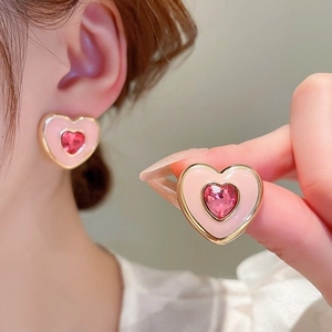 Detail of pink enamel heart earrings with red crystal center and golden metal border