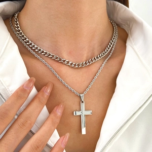 Detail of layered silver necklaces with chunky Cuban chain and cross pendant on model