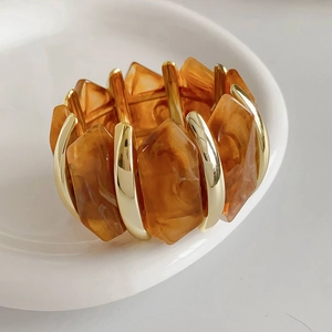Vue macro de blocs de résine ambre et d'entretoises dorées sur un bracelet élastique
