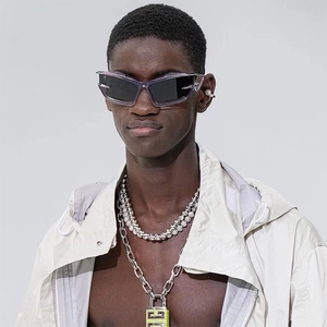 Close-up of futuristic purple sunglasses with thick silver padlock and curb chain necklaces