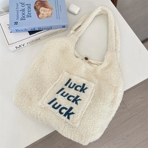 Detail of white faux fur tote bag with luck embroidery and magnetic closure button