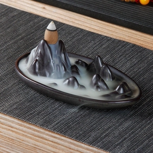 Dettaglio del bruciatore di incenso a forma di montagna con fumo su ceramica scura