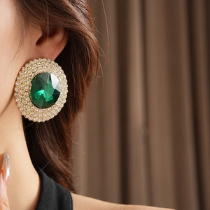 Macro shot of gold emerald stud earrings with sparkling crystals for elegant evening wear