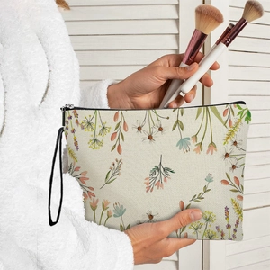 Floral canvas makeup bag with black zipper and wristlet strap held by a model