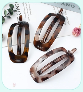 Three oval leopard print hair clips displayed on a stylish lifestyle background