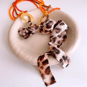 Bohemian orange beaded necklace with gold oval metal rings and leopard print silk ribbon