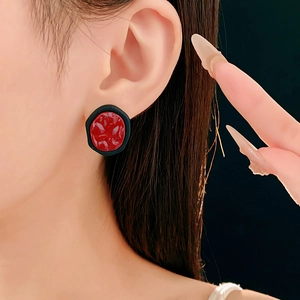 Détail macro de boucles d'oreilles rondes avec texture rouge et fini noir mat