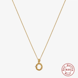 Macro detail of gold 925 sterling silver necklace showing textured letter O and diamonds
