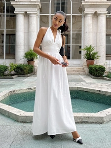 Detail of a white halter neck cotton maxi dress with a deep V-neck and a flowing A-line skirt