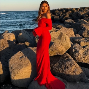 Elegant red off-shoulder maxi dress with flare sleeves against a sunset beach backdrop
