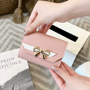 Pink lychee texture leather wallet held by hand with bow tie and ribbon details