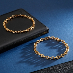Polished gold titanium steel O-chain and oval link bracelets on blue background