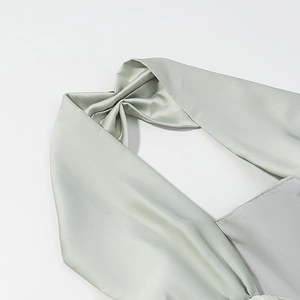 Detailaufnahme der hellgrünen Satin-Neckholder-Bänder mit glatter Stofftextur und Glanz