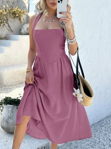 Pink halter neck maxi dress featuring high waist and flowy skirt in a sunlit resort setting